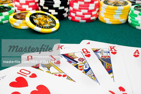 royal flush and unfocused gambling chips of a green fabric background