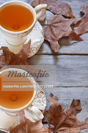 Green tea in vintage mugs on wooden table with dry fall leaves. Copy space background.