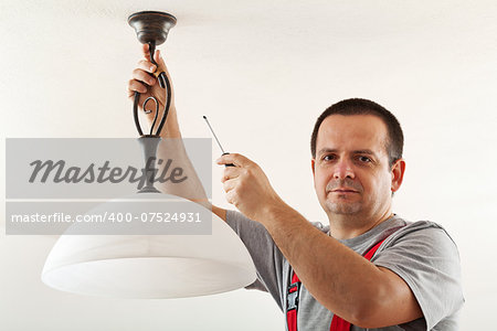 Electrician mounting ceiling lamp - closeup