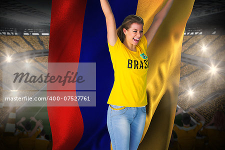 Excited football fan in brasil tshirt holding colombia flag against vast football stadium with fans in yellow