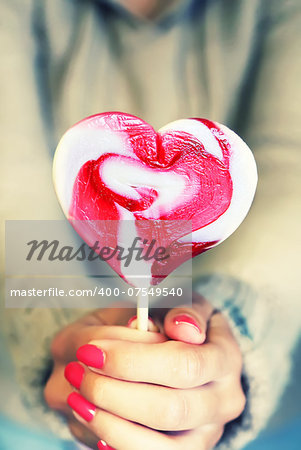 Photo of girl holding heart shaped lollipop