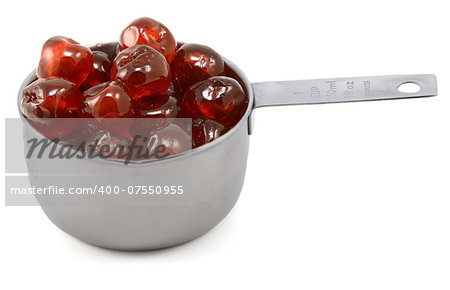 Sticky whole glace cherries in an American cup measure, isolated on a white background