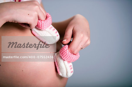 Pregnant woman holding a pair of pink baby booties