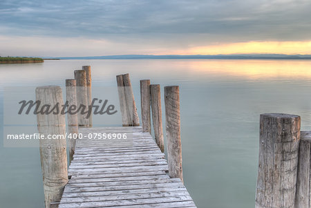 wooden pier with columns on the lake at sunset