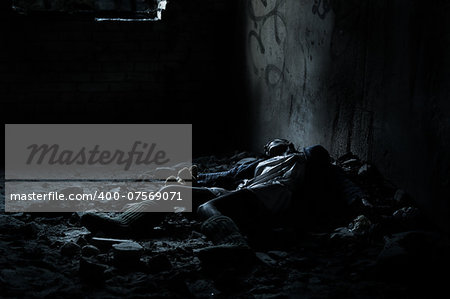 Dead woman lying on the dirty floor in a heap of rubbish in the basement