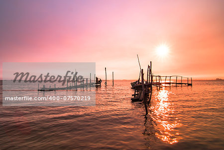 Old fishing dock sunrise and calm water reflection.