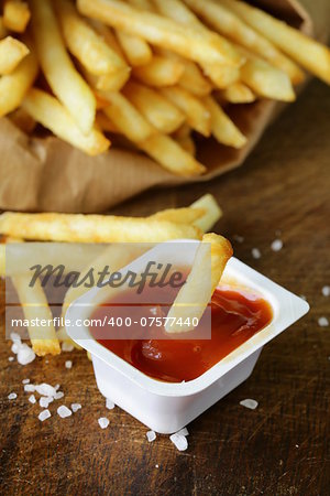 Traditional potatoes French fries with salt on wooden background