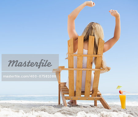 Pretty blonde sitting in deck chair with a cocktail on a sunny day