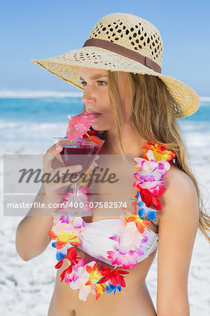 Pretty blonde in floral garland sipping cocktail on the beach on a sunny day