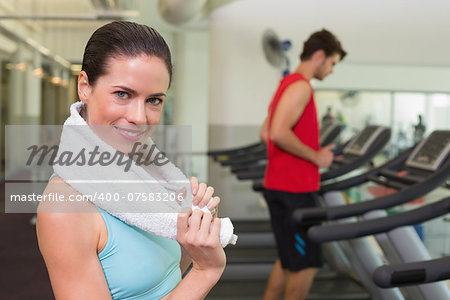 Smiling brunette with towel over shoulders at the gym