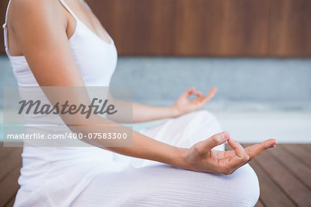 Peaceful woman in white sitting in lotus pose in health spa