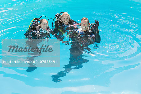 Smiling friends on scuba training in swimming pool on a sunny day
