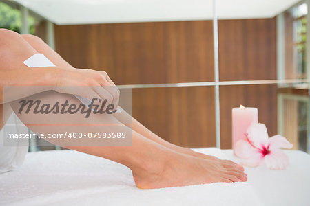 Woman waxing her legs herself in the health spa