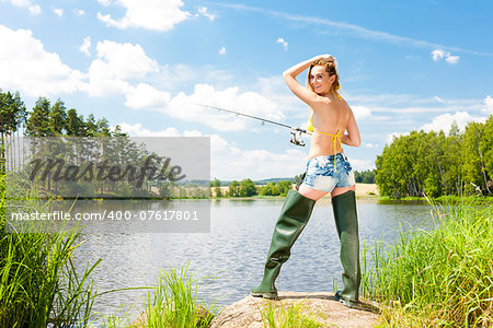 young woman fishing at pond in summer