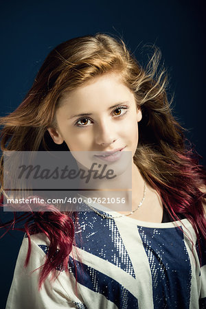 Studio fashion portrait of young beautiful girl with nice eyes on dark blue background with wind from fan in hair