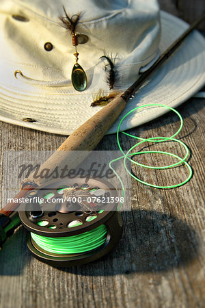 Close-up of fly-fishing reel and rod with canvas hat