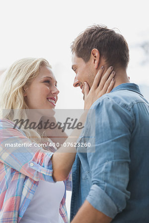 Cute young couple standing and facing each other on a sunny day in the city