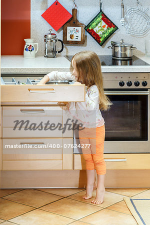 Little girl getting tableware from table case before dinner