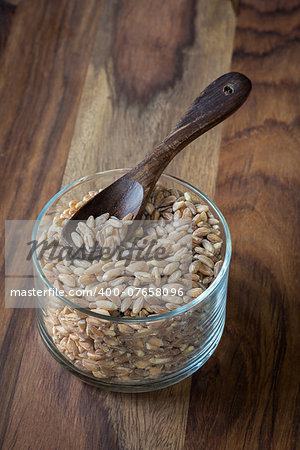 Loose grains of farro in a bowl with a spoon.