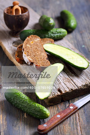 Cucumbers and black bread on an old board.