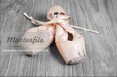 Old used  ballet pointe shoes on vintage wooden background