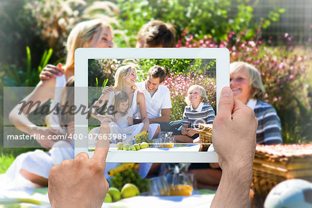 Hand holding tablet pc showing happy family having a picnic