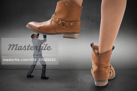 Composite image of cowboy boots stepping on businessman on grey background