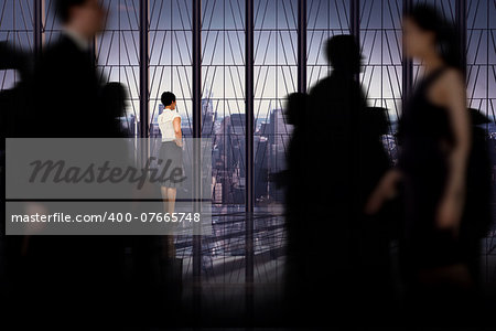 Business people walking in a blur against room with large window looking on city