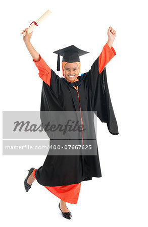 Portrait of full length smiling Asian female Muslim student in graduate gown hands raised showing graduation diploma jumping isolated on white background.
