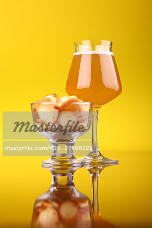 Glass of wheat beer with snack over a yellow background