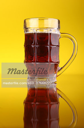 Glass of dark beer over a bright yellow background
