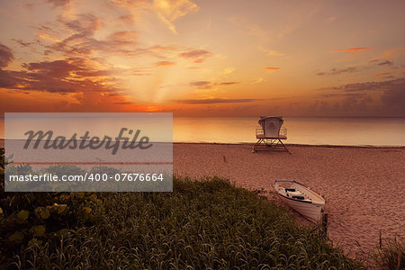Tropical beach at beautiful sunrise. Nature background with lifeguard station and boat at Palm Beach, Florida, United States.