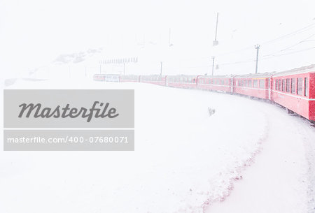 The famous Bernina red train, Unesco monument, in the middle of a winter storm