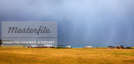 Small fishing village on the west coast of Iceland with heavy rain in the background