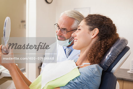 Patient admiring her new smile in the mirror at the dental clinic