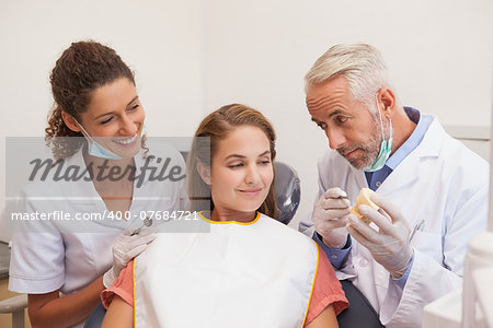 Dentist and assistant smiling with patient in chair at the dental clinic
