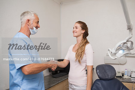 Dentist shaking hands with his patient at the dental clinic
