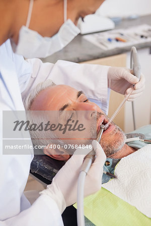 Dentist examining a patients teeth in the dentists chair at the dental clinic