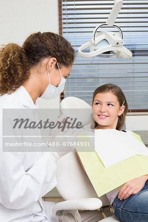 Pediatric dentist speaking with little girl in the dentists chair at the dental clinic