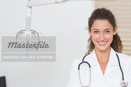 Dental assistant smiling at camera beside light at the dental clinic
