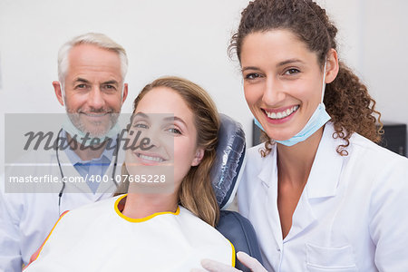 Dentist his assistant and patient all smiling at camera at the dental clinic