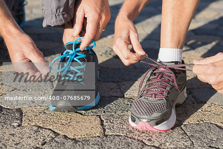 Couple tying their laces of running shoes on a sunny day