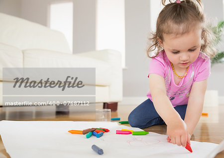 Little girl drawing in the living room at home