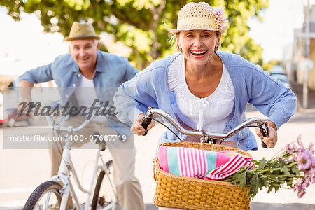 Happy mature couple going for a bike ride in the city on a sunny day