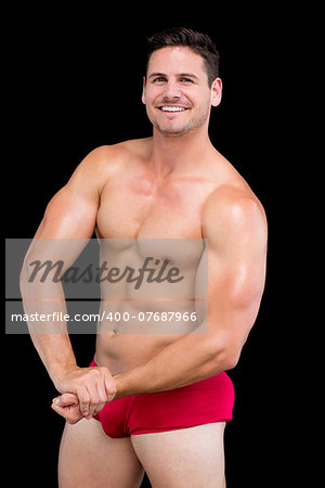 Portrait of a shirtless muscular man standing over black background