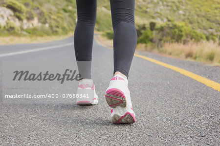 Rear view low section of fit young woman running on the open road