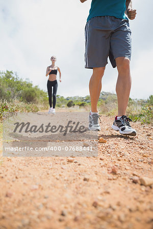 Low angle view of fit young couple running on countryside road