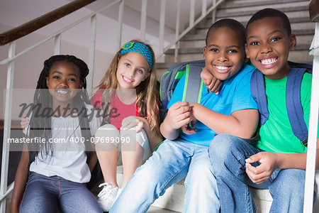 Cute pupils smiling at camera on the stairs at the elementary school