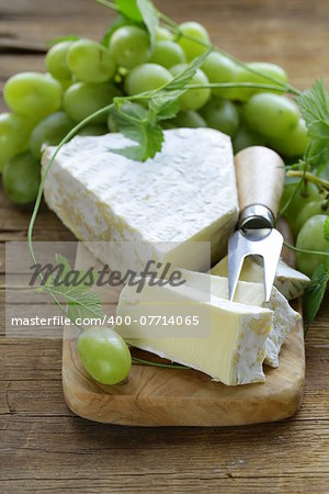 Soft brie cheese with sweet grapes on a wooden board