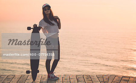 Beautiful fashion skater girl posing with  a skate board